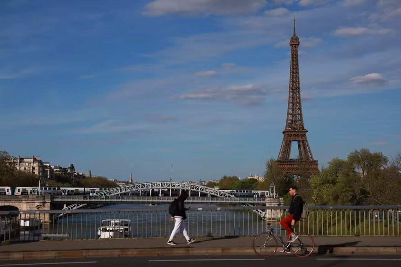 Um pedestre caminha enquanto um ciclista anda de bicicleta pela Pont de Grenelle sobre o rio Sena, em Paris — Foto: Emmanuel Dunand / AFP